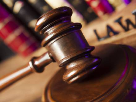 A gavel resting on a wooden block, with law books in the background.